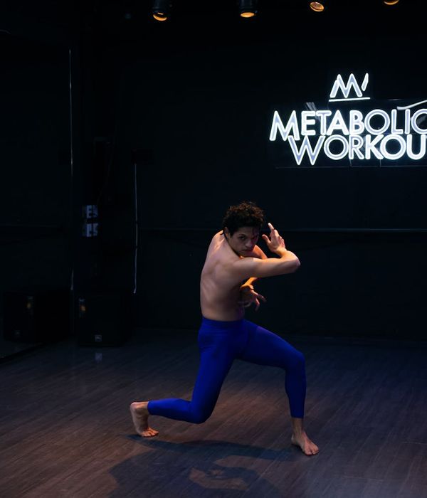 Man performing a controlled strength exercise in a dark studio setting.
